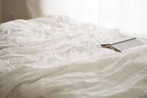 An open book laying on a bed with white sheets