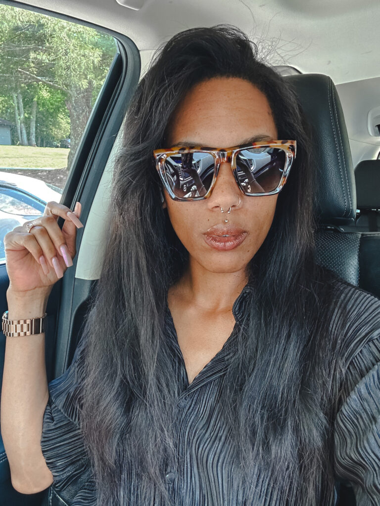 girl with long black hair sitting in her car wearing Sojos cat eye sunglasses 