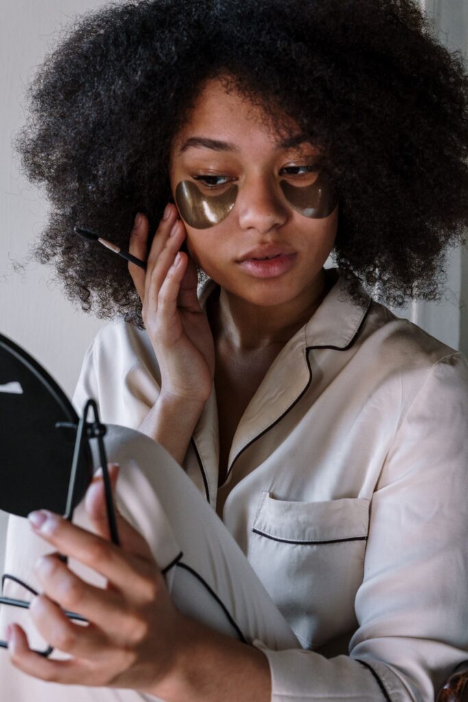 woman with eye patches on looking in a mirror